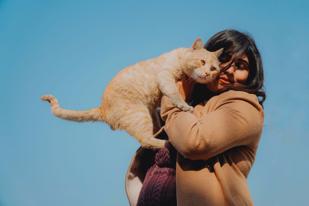 Mujer con su gato naranja sobre el hombro